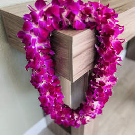 Magenta orchid lei draped over a wooden post
