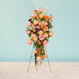 Tall standing floral spray with pink and orange roses on a metal easel
