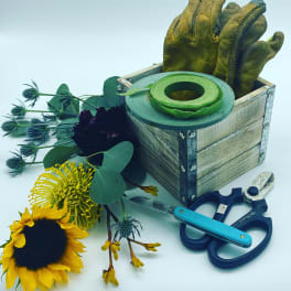 Sunflower and assorted stems with floral tools in a wooden box