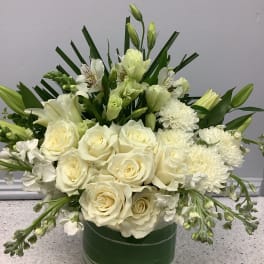 White roses and lilies arranged in a green glass vase