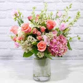 Pink and peach roses with hydrangea in a clear glass vase