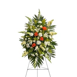 Standing floral spray with white lilies, orange roses, and white blooms
