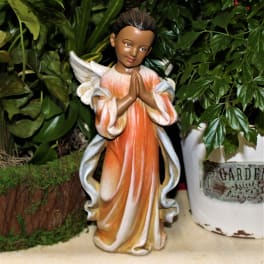 Angel figurine in an orange and white robe surrounded by potted greenery