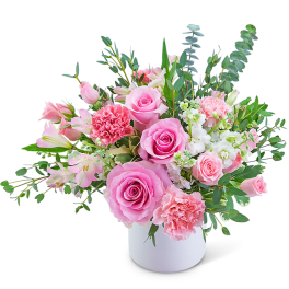 Pink roses and carnations in a white vase with mixed greenery
