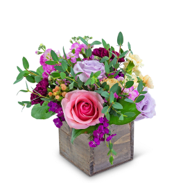 Mixed pink, lavender, and yellow flowers in a wooden box
