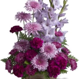 Purple and pink mixed flower arrangement in a decorative vase