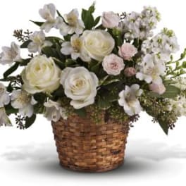 White roses and pale flowers arranged in a woven basket