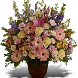 Mixed pink and cream flowers arranged in a brown urn vase