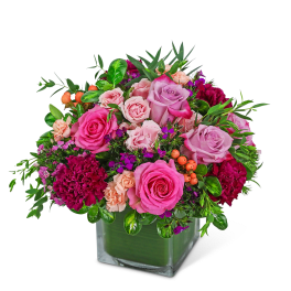 Pink and lavender roses with carnations in a square glass vase