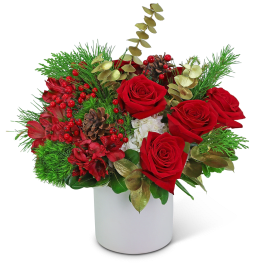 Red roses and berries in a white vase with pinecones and greenery
