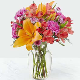 Bouquet of orange lilies and pink alstroemeria in a clear glass vase