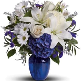 White lilies and daisies with blue hydrangea in a blue vase