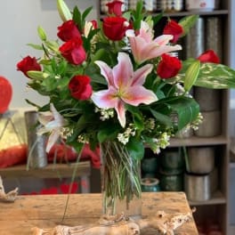 Bouquet of red roses and pink lilies in a clear glass vase