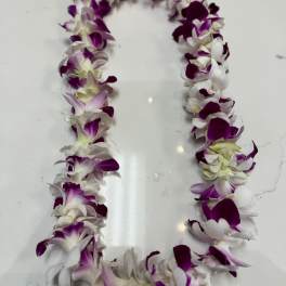 Purple and white orchid lei laid in a loop on a white surface