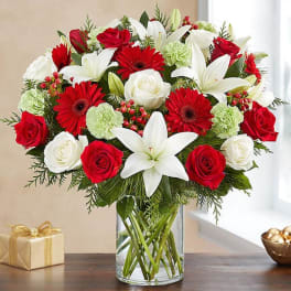 Bouquet of red roses, white lilies, and red gerbera daisies in a glass vase