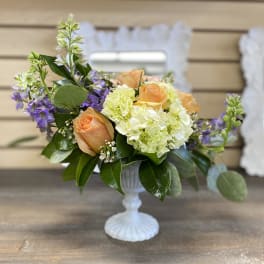 Peach roses and pale hydrangeas in a white pedestal vase