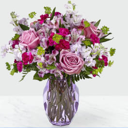 Pink and lavender mixed bouquet in a purple glass vase