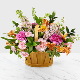 Mixed pink and orange flowers in a wooden basket