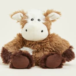 Brown and white plush cow toy sitting against a plain background