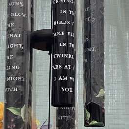Hanging black wind chimes with floral accents and a small wooden tag