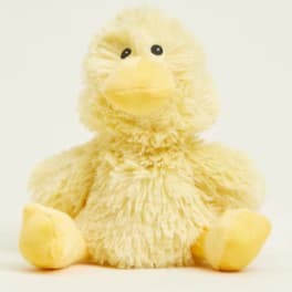 Yellow plush duck with black eyes sitting on a plain background
