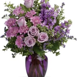 Lavender roses and purple flowers in a purple glass vase