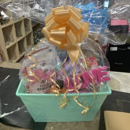 Gift basket with skincare items wrapped in clear cellophane and topped with a gold bow