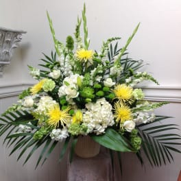 Large white and green floral arrangement with yellow blooms in a vase