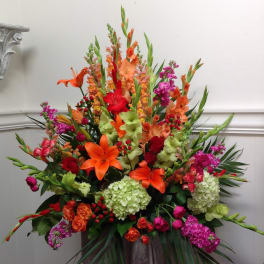 Large arrangement of orange, red, pink, and green flowers in a vase