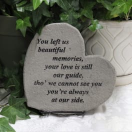 Heart-shaped memorial stone with engraved sympathy message beside potted ivy