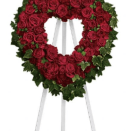 Heart-shaped red rose wreath on a white easel