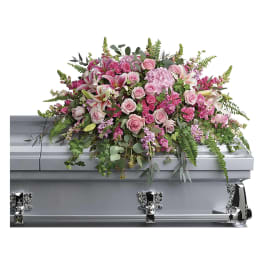 Large pink and white casket spray with roses and lilies on a gray casket