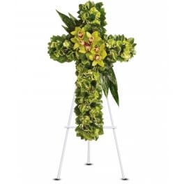 Green floral cross with clustered orchids displayed on a white metal easel