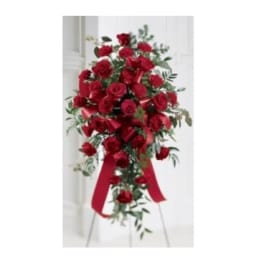 Tall standing spray of red roses with red ribbon on a metal easel.