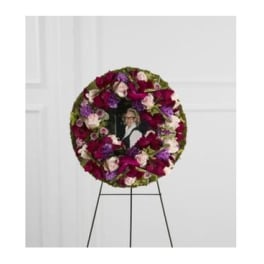 Circular floral wreath on an easel with a photo in the center