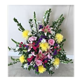 Large floral spray with pink lilies, roses, and yellow blooms