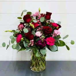 Bouquet of red roses and pink flowers in a clear glass vase