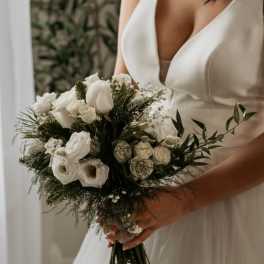 Bride holding a white bouquet with roses and small filler flowers