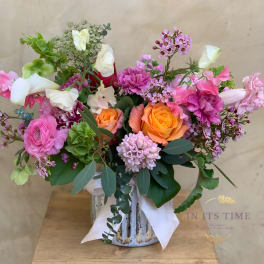 Mixed bouquet of pink, orange, and white flowers in a ceramic vase