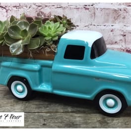 Succulents arranged in a turquoise ceramic pickup truck planter