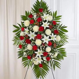 Standing floral spray with red roses and white lilies on an easel