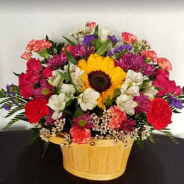 Mixed bouquet in a wooden basket with a sunflower, roses, and white blooms
