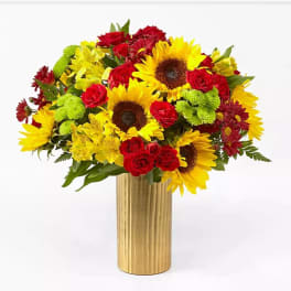 Bouquet of sunflowers, red roses, and yellow flowers in a gold vase
