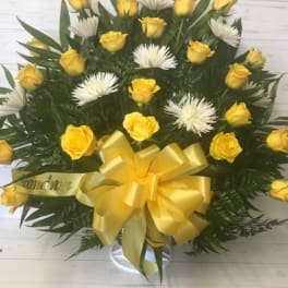 Yellow roses and white spider mums in a round arrangement with a yellow bow