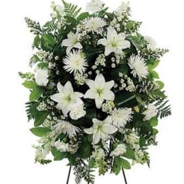 White funeral spray with lilies and daisies on a stand