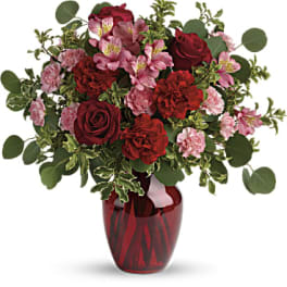 Red and pink mixed bouquet in a red glass vase