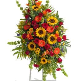 Large standing floral spray with sunflowers, red roses, and orange blooms