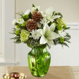 White lilies and green roses in a green glass vase with pinecones