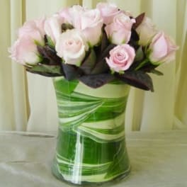 Pink and white roses arranged in a green glass vase