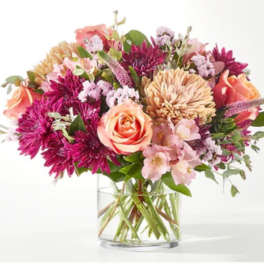 Mixed pink and peach flowers in a clear glass vase